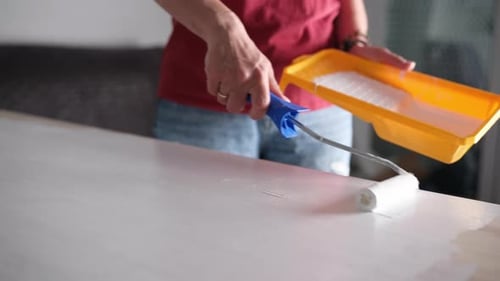 Person Painting Table with Roller in Home