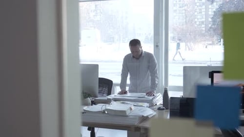 Man standing looking at papers in office in winter