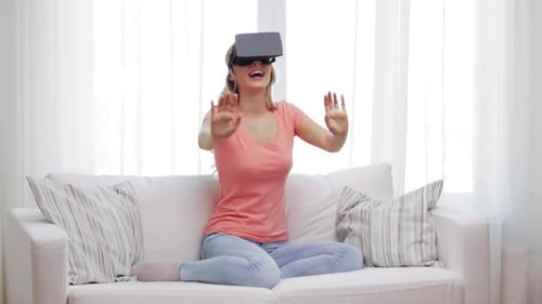 Smiling woman uses VR headset sitting on sofa