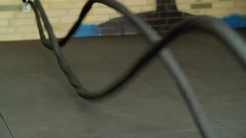 A Muscular White Man Does Battle Rope Exercises at a Gym