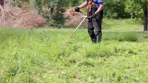 Man Trimming Grass in Sunny Rural Field