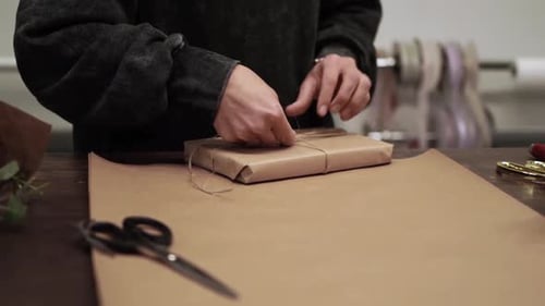 Person Tying Twine Around Small Wrapped Gift