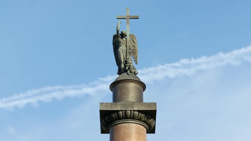 Angel Statue Holds Cross Against Blue Sky