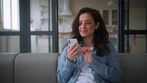 Young Woman Using Smartphone on Couch at Home