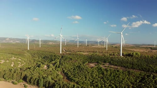 Aerial shot of wind mills rotating by the force of the wind and generating renewable energy in a g