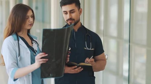 Healthcare Professionals Examining X-Ray in Hospital Hallway