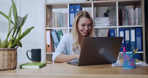 Une jeune femme travaille assidûment sur son ordinateur portable dans un espace de bureau moderne