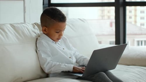 Boy Engaged in Learning at Home While Using a Laptop Alone