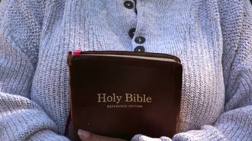 Person Holding Brown Holy Bible Outdoors