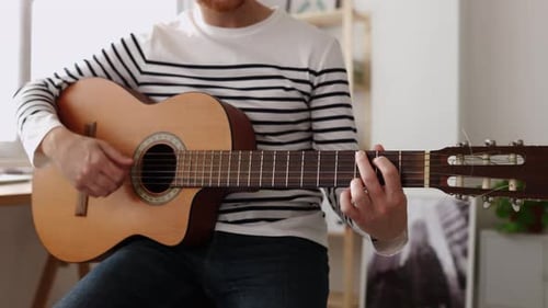Closeup View of Young Man Playing the Guitar at Home