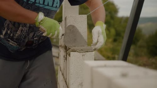 Worker constructs concrete brick wall for house building project