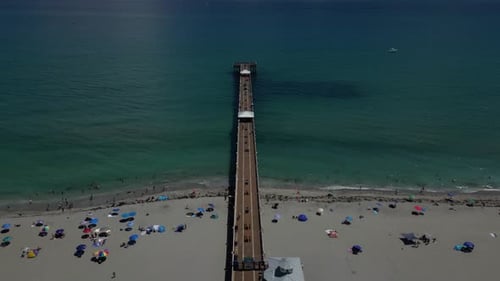 Imagens aéreas de Drone com uma foto de Dolly e um longo cais estendido ao longo da praia com pessoas. Simétrico