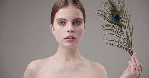 Young Woman Posing With Peacock Feather Close Up