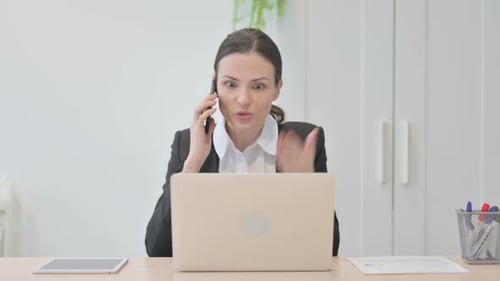 Woman Arguing on Phone at Office Desk