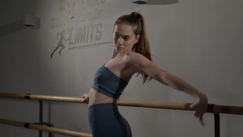 Woman Stretching at Ballet Barre in Workout Studio