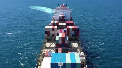 Aerial footage of a container ship approaching a commercial port.