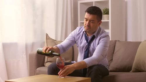 Man Pours Wine, Drinks on Couch at Home