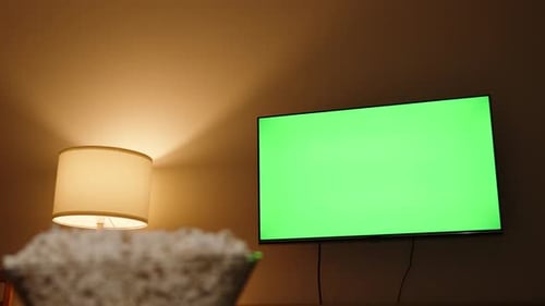 Selective Focus of the Camera on the Green TV Screen, and a Hand in the Foreground Takes Popcorn.