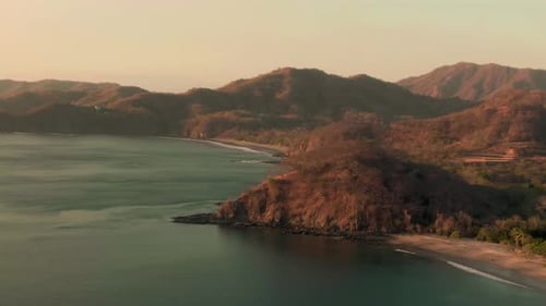 Aerial parallax motion shot of rocky Costa Rican beach line in sunset