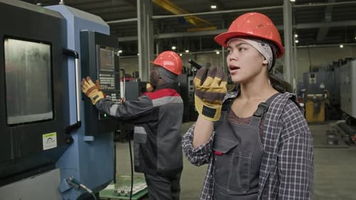 Young Workwoman in Hardhat Communicating with Coworkers via Walkie-Talkie