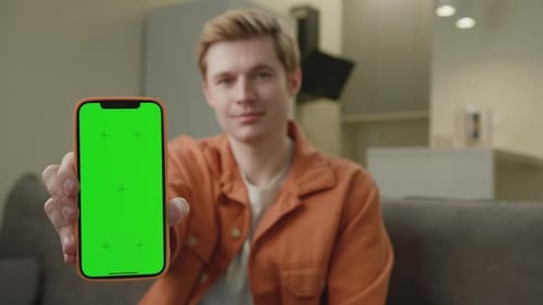Man Holding Green Screen Smartphone At Camera Smiling White Man Shows Chroma Key Screen at Camera