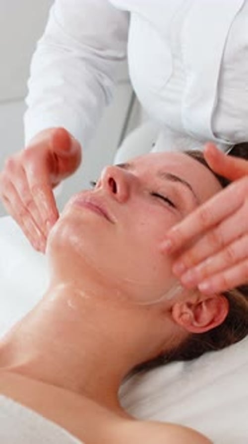 Beautician Facial Massage with Moisturizing Oil for Middle Aged Young Woman in Cosmetology Clinic