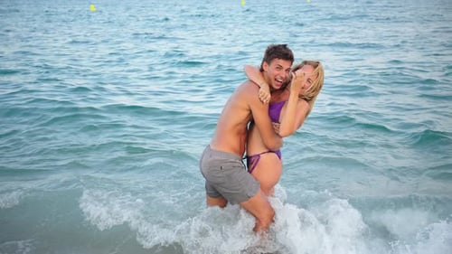 Joyful Couple Enjoying a Sunny Day at the Beach While Embracing Each Other in the Gentle Waves
