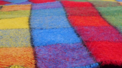 Close-up view on the bright textured multicolored wool fabric in a large check rotated