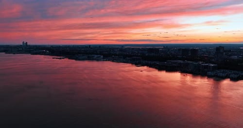 Pink sky reflecting in the waterscape of the river. Fantastic view of metropolis at dusk. Top view.