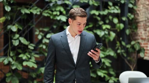 Excited Businessman Celebrates Success on Phone in Modern Office