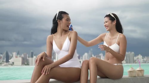 Female friends spend leisure activity at rooftop swimming pool.