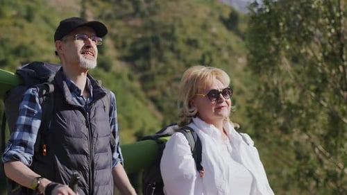Senior Man Points a Finger at the Mountain Talking with the Woman About the Local Area During the