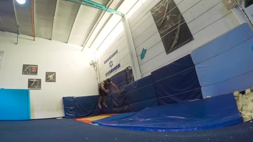 Man Practices Gymnastics Backflips in Training Facility