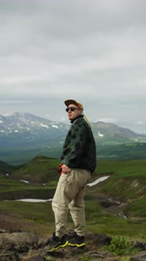 Solo Hiker Standing on Rocky Ridge in Remote Green Mountains Wearing Casual Outdoor Clothing and