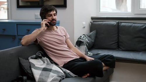 Young Adult Talking on Phone Relaxing on Sofa