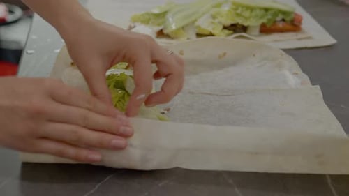Una mujer enrolla kebab en lavash con verduras y hierbas frescas para un delicioso envoltorio