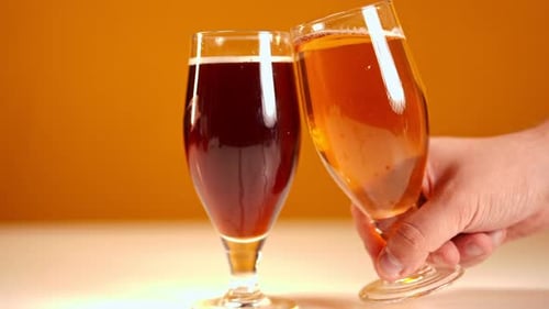 Bière brune en gros plan avec un verre de bière blonde à la main d'un homme, laissant méconnaissable au ralenti