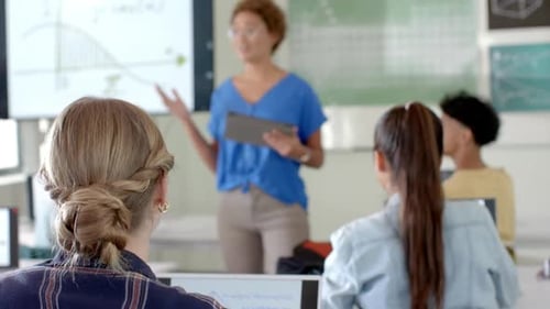 In high school, students raising hands to answer teacher's question in classroom