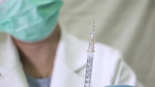 Medizinisches Fachpersonal entfernt Luftblasen aus einer gefüllten Spritze, um die Genauigkeit zu gewährleisten