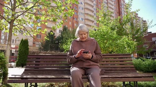 Senior Woman Using Smartphone on Park Bench