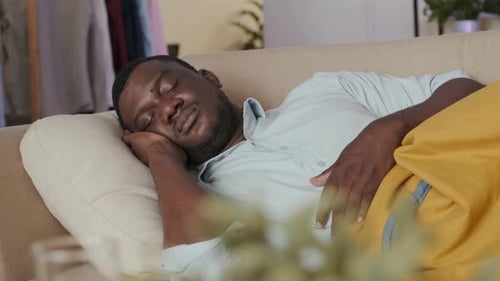 Homme noir dormant sur un canapé dans le salon