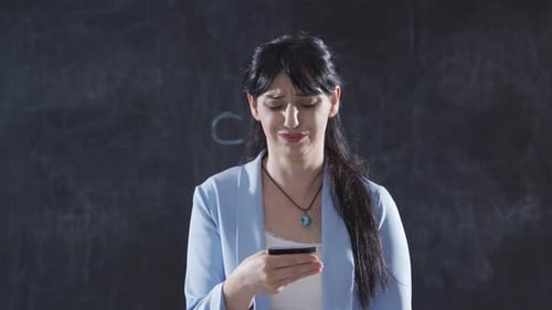 The woman who writes Credit card victim on the blackboard looks up with a sad expression.