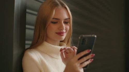 Blonde Woman Smiles While Looking at Phone