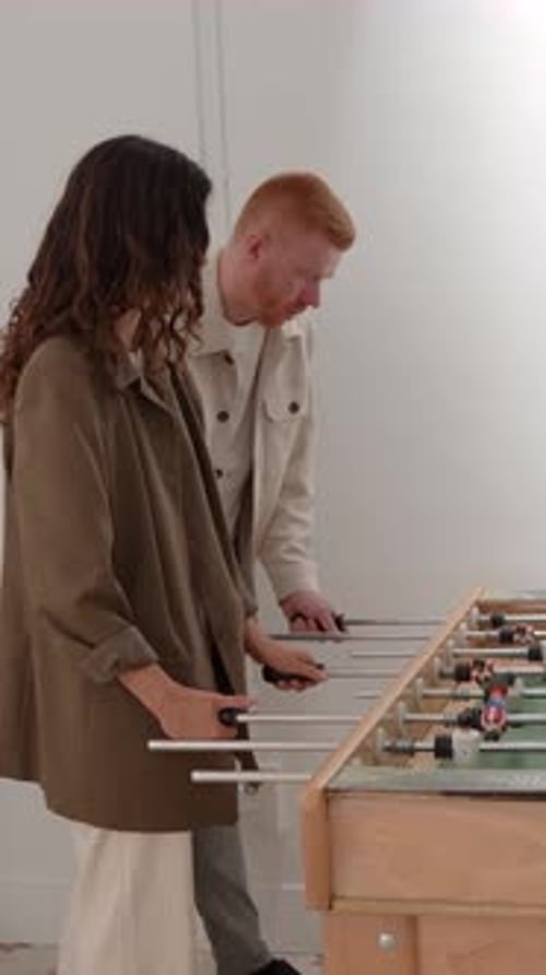Coworkers Playing Foosball in an Office Break Room