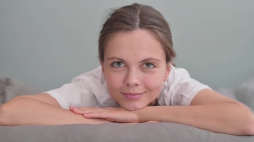 Smiling Young Woman Lying on Stomach in Bed