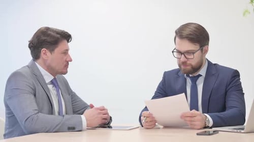 Businessmen Reviewing Documents and Making a Deal