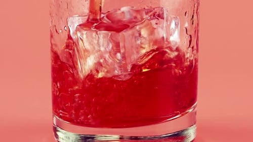 Red Beverage Poured Over Ice Cubes in Glass