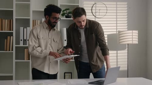 Two Businessmen Business Partners Excited Multiracial Men Talk in Office Discuss Project on Laptop