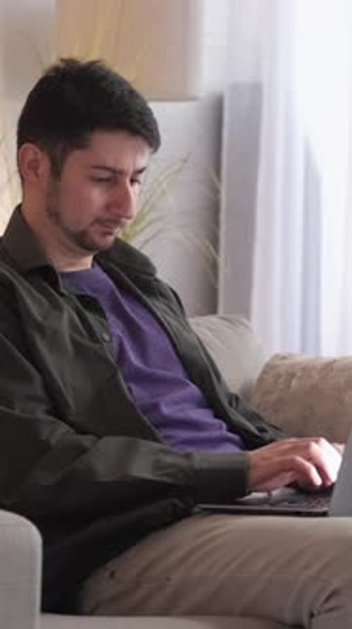 Man Using Laptop on Couch Indoors