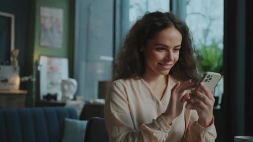 Smiling woman using her smartphone indoors